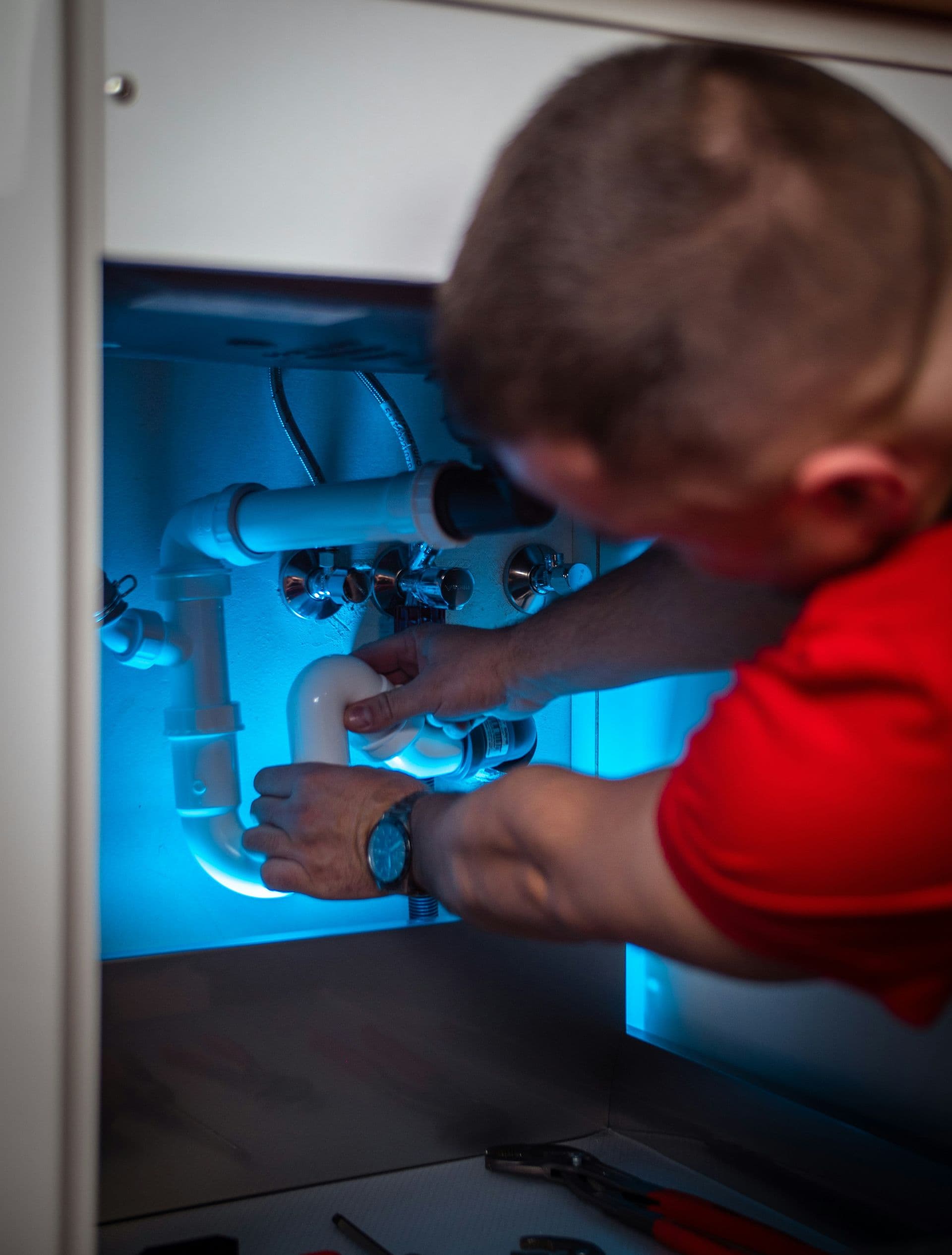 Plumber working on pipes under kitchen sink
