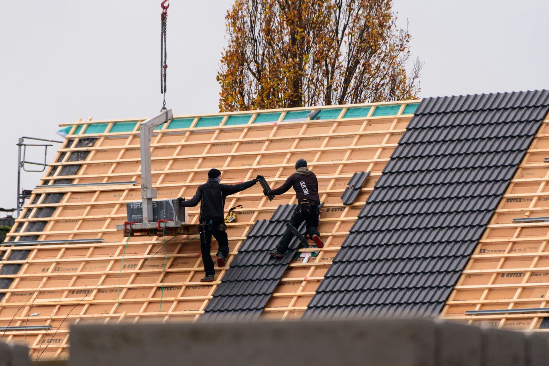 Roofers installing roof tiles on residential building